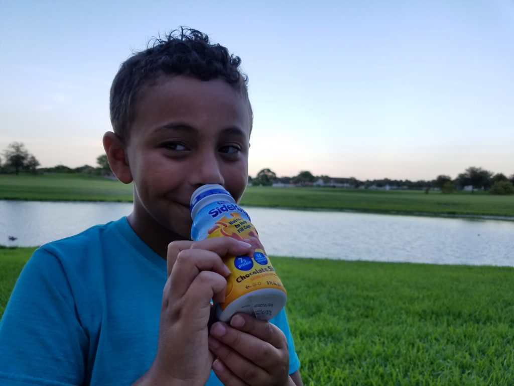 son drinking Pediasure Sidekicks outside